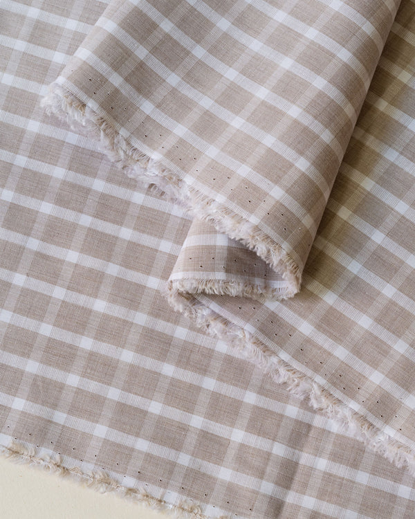 Close up image of beige and white check deadstock cotton fabric for sewing home made clothes 